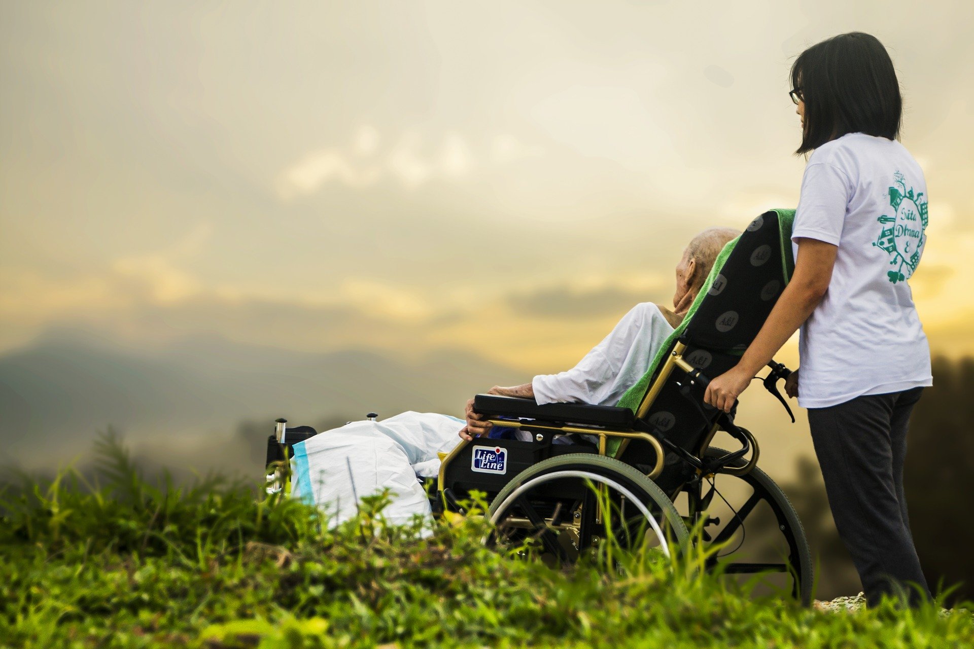 Symbolbild: Eine Krankenschwester schiebt einen Patienten im Rollstuhl, Link zur Seite "Ausbildungsberufe im Gesundheitswesen"