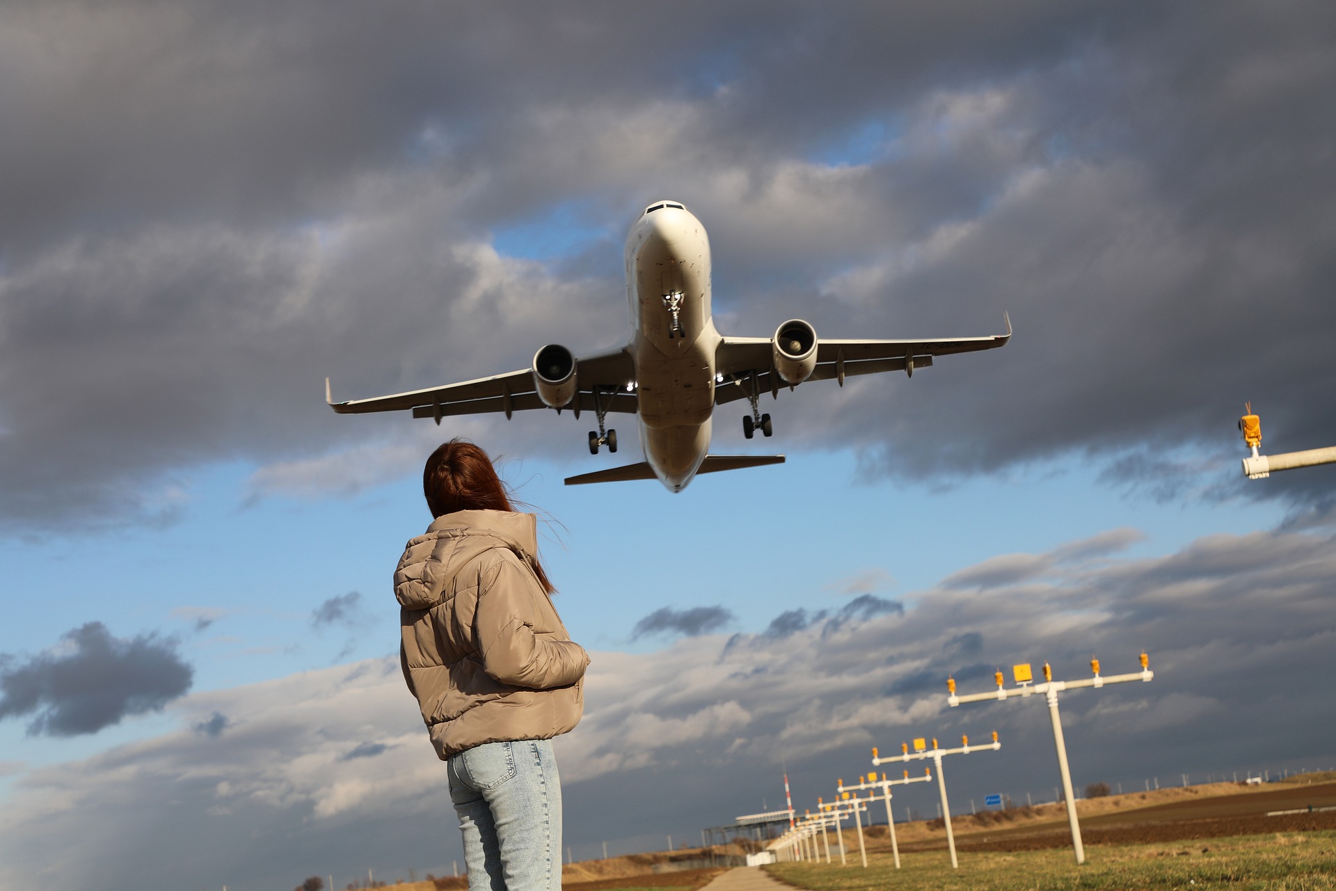 Person in direkter Nähe zu einem landenden Flugzeug als Symbolbild für Fluglärm