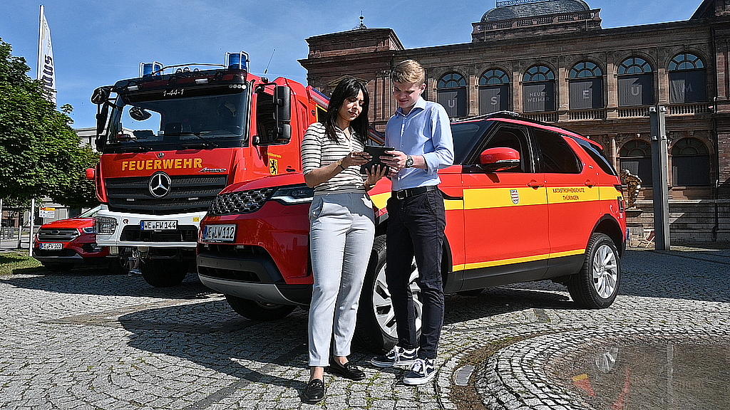 Eine Anwärterin und ein Anwärter vor einem Katastrophenschutzfahrzeug, Link zur Seite "Dein Studium"