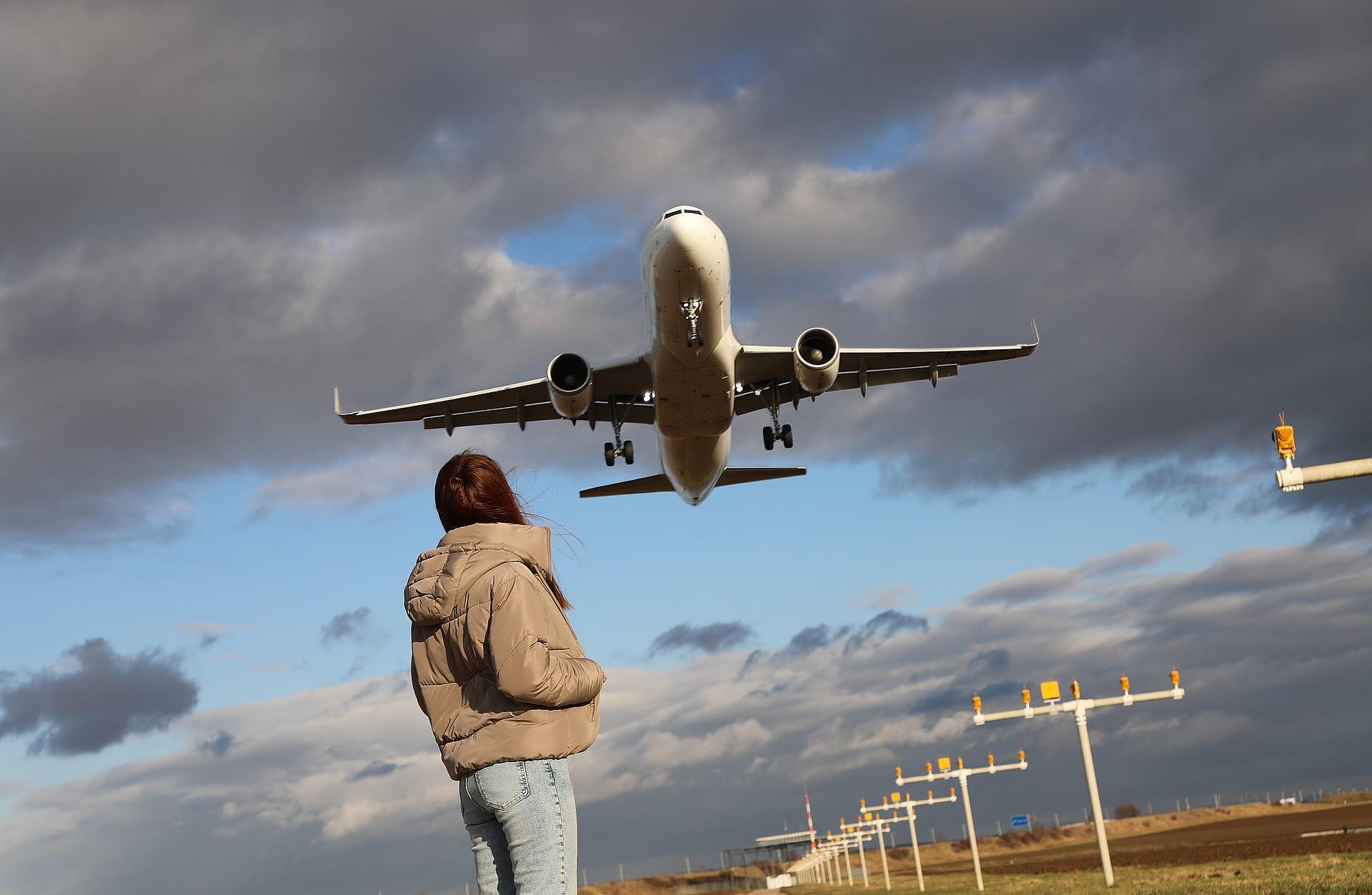 Person in direkter Nähe zu einem landendem Flugzeug als Symbolbild für Fluglärm